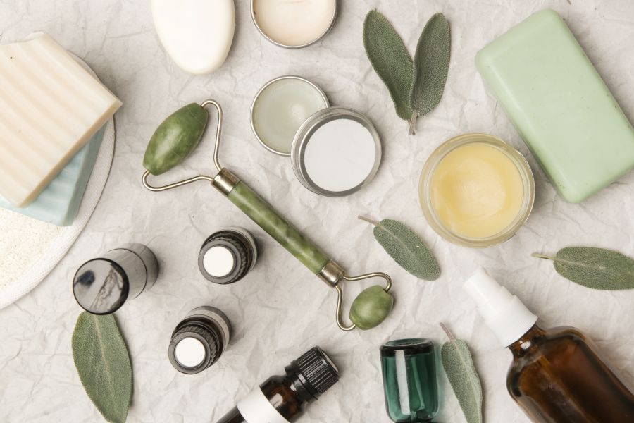 various cosmetics products scattered with green leaves